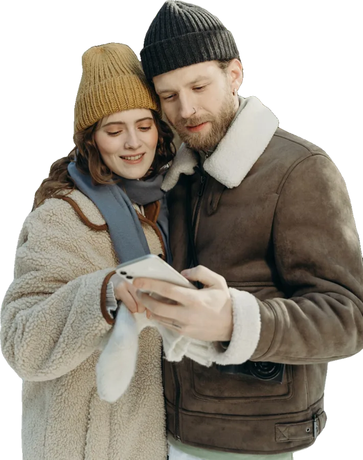 A couple in winter coats looking at a phone together